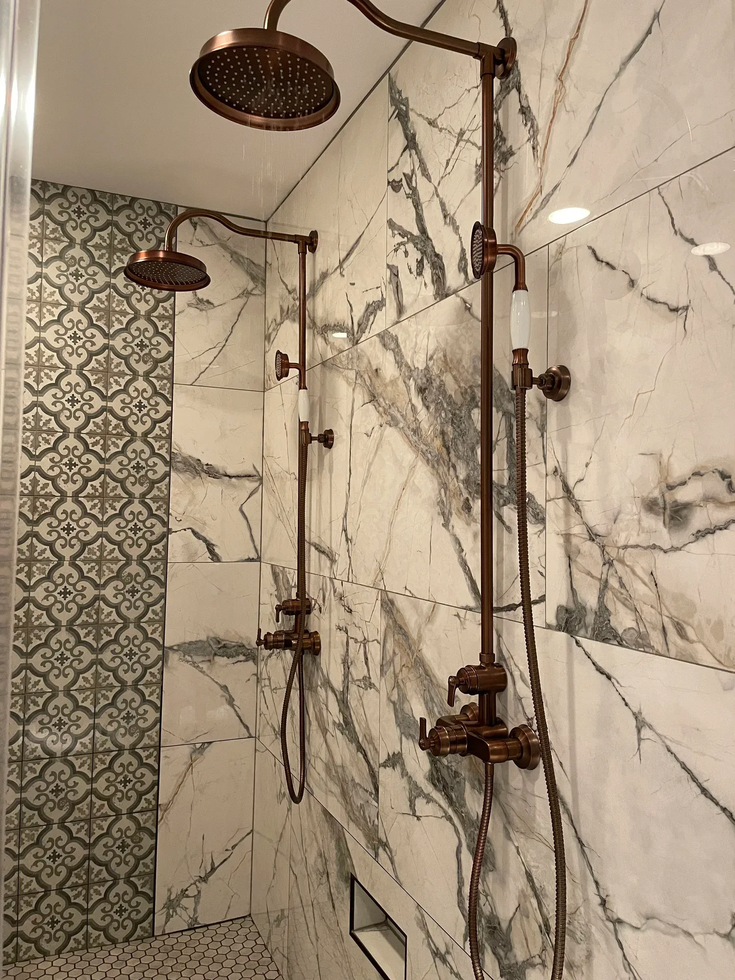 Luxury walk-in shower with marble walls and antique copper fixtures, remodeled by Hale Development